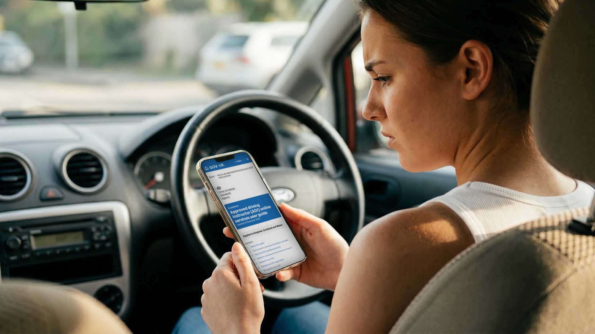 A frustrated learner driver looking at a phone, warning about learner driver scams