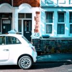 A modern car parked safely on a residential road in the UK, representing a learner driver preparing to book their practical test under the new official DVSA driving test booking rules.